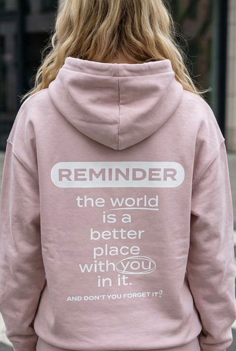 Person wearing a pink hoodie with a motivational message on the back.