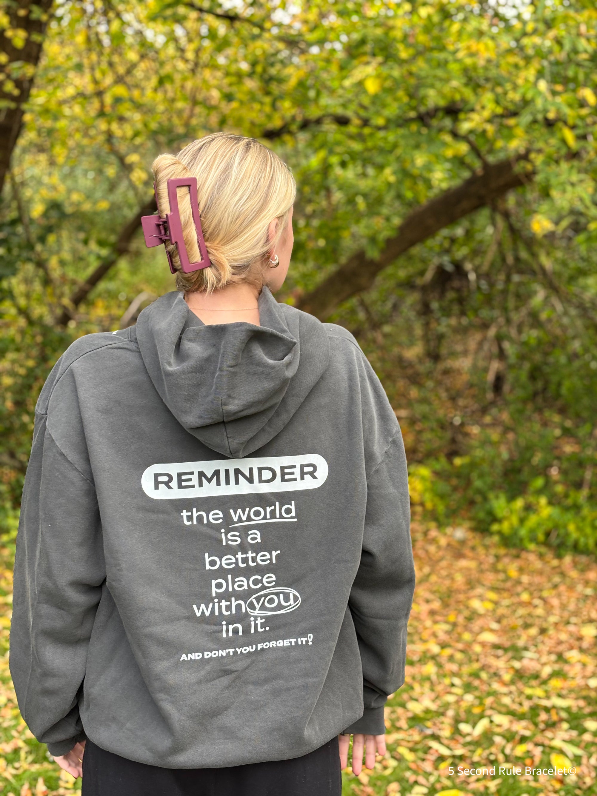 Person wearing a gray hoodie with a motivational message in an outdoor setting
