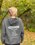 Person wearing a gray hoodie with a motivational message in an outdoor setting