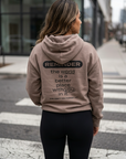 Person wearing a hoodie with a motivational message on a city street.