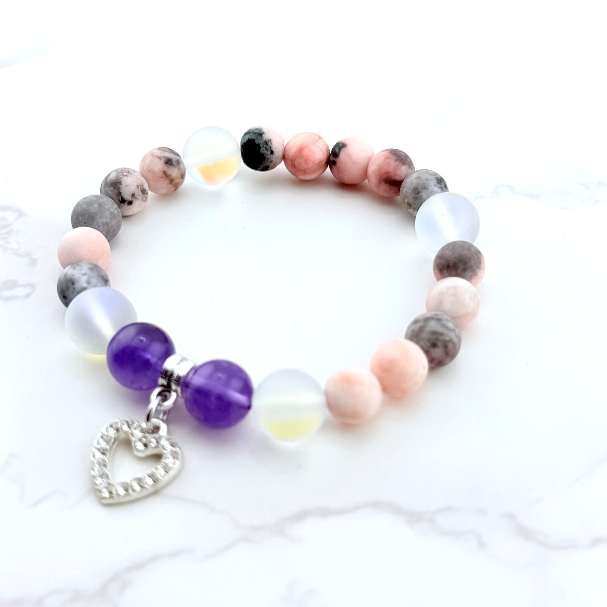 Multicolored beaded bracelet with a heart charm on a white background