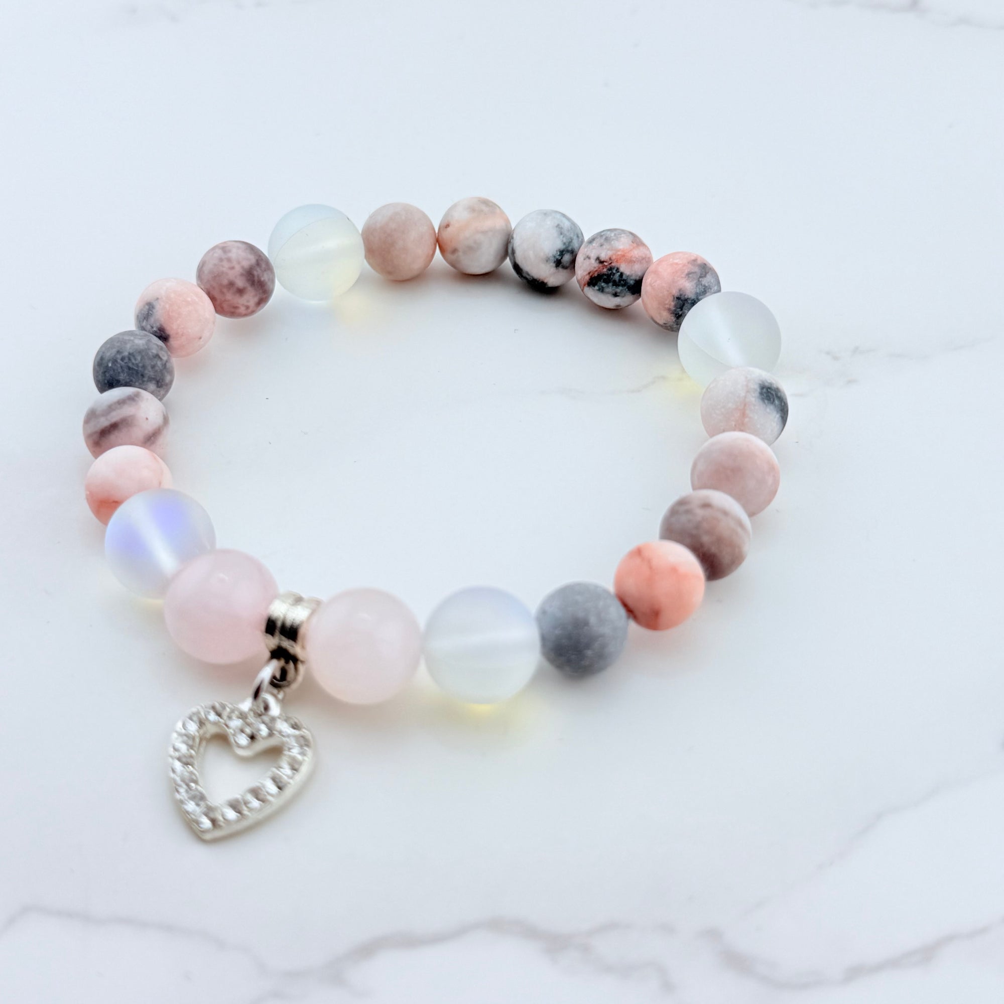 Beaded bracelet with a heart charm on a marble surface