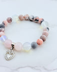 Beaded bracelet with a heart charm on a marble surface