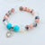 Beaded bracelet with turquoise beads and a heart charm on a light background