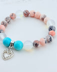 Beaded bracelet with turquoise beads and a heart charm on a light background