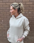 Person wearing a light tan hoodie with text on a brick pavement