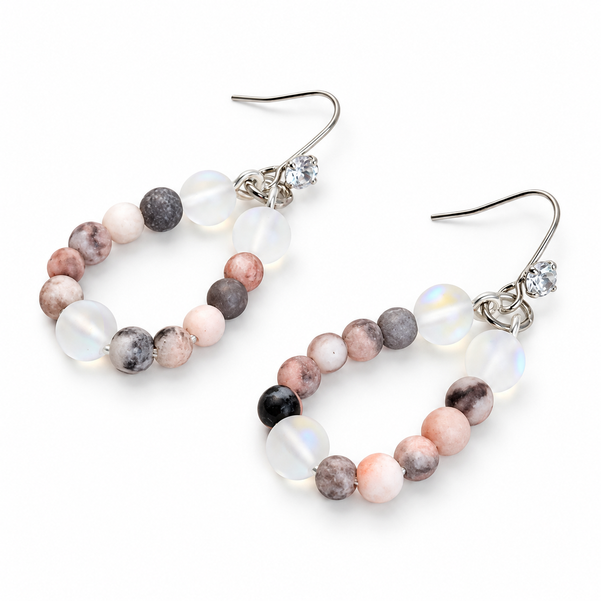 A pair of drop earrings with irregular polished beads in pink, gray, white, and black, suspended from silver fishhook wires with small clear rhinestone accents, shown on a white background.
