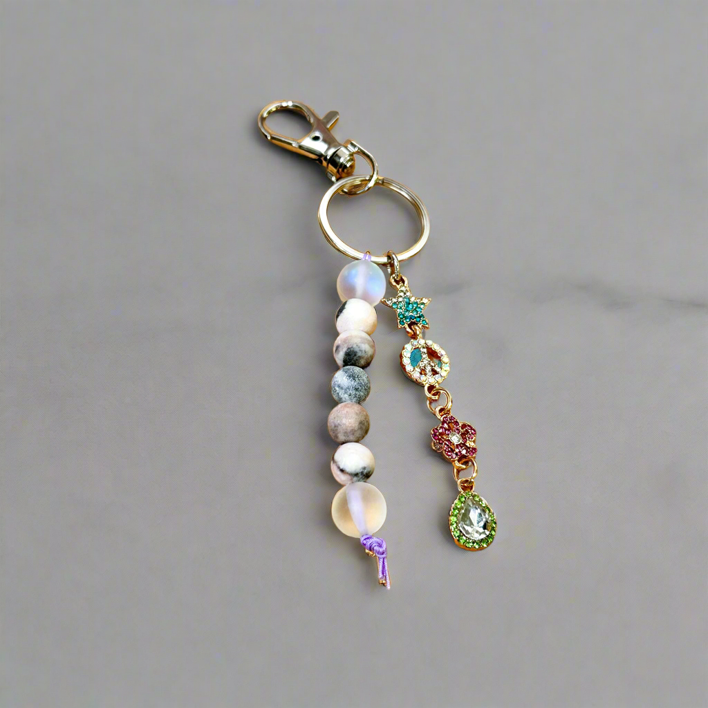 A colorful keychain with a heart-shaped pendant, featuring a mix of beads and a crystal-like star charm, displayed on a wooden surface.