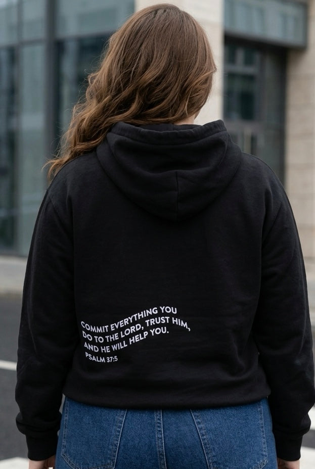 Person wearing a black hoodie with text on the back, standing outdoors.