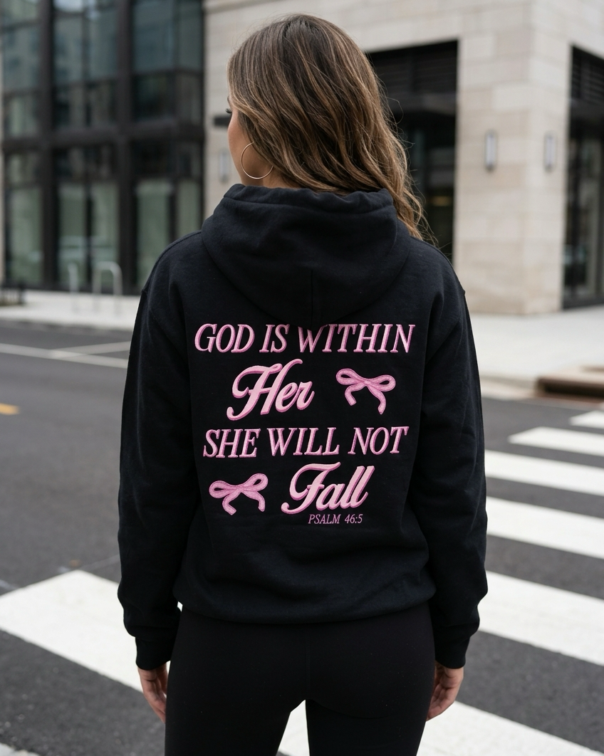 Person wearing a black hoodie with a motivational quote on the back, standing on a street.