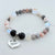 Beaded bracelet with 'Mom' charm on a light background