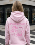 Person wearing a pink hoodie with text on the back, standing on a street.