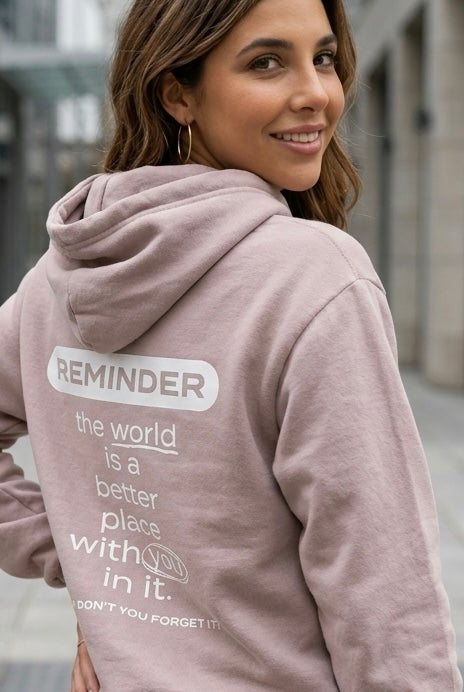 Woman wearing a hoodie with a motivational message on the back, standing outdoors.