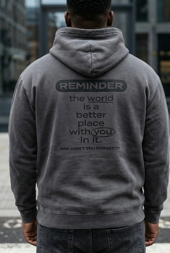 Person wearing a gray hoodie with a motivational message on the back, standing outdoors.