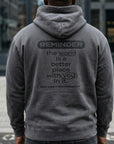 Person wearing a gray hoodie with a motivational message on the back, standing outdoors.