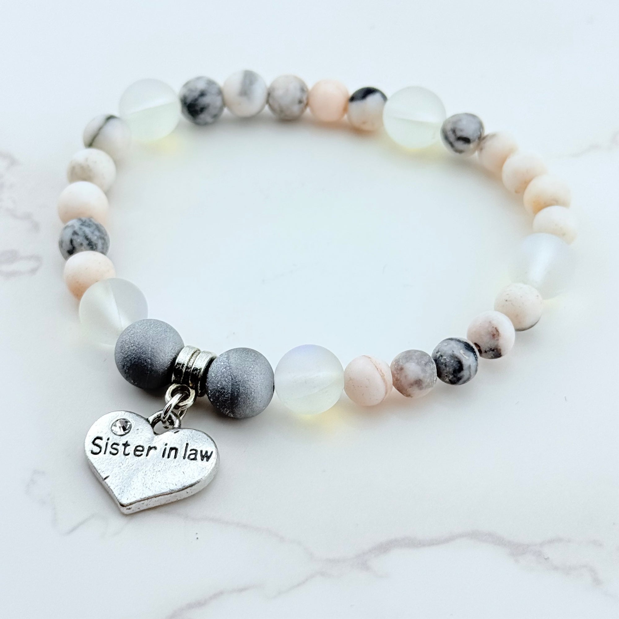 Beaded bracelet with a heart-shaped 'Sister in Law' charm on a white marble background