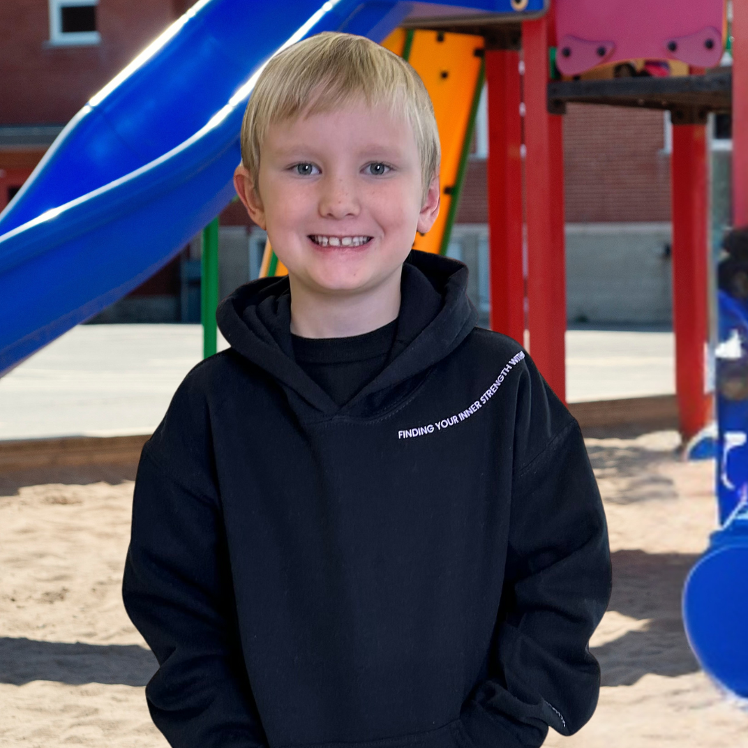 Young boy wearing a black hoodie with text on a playground