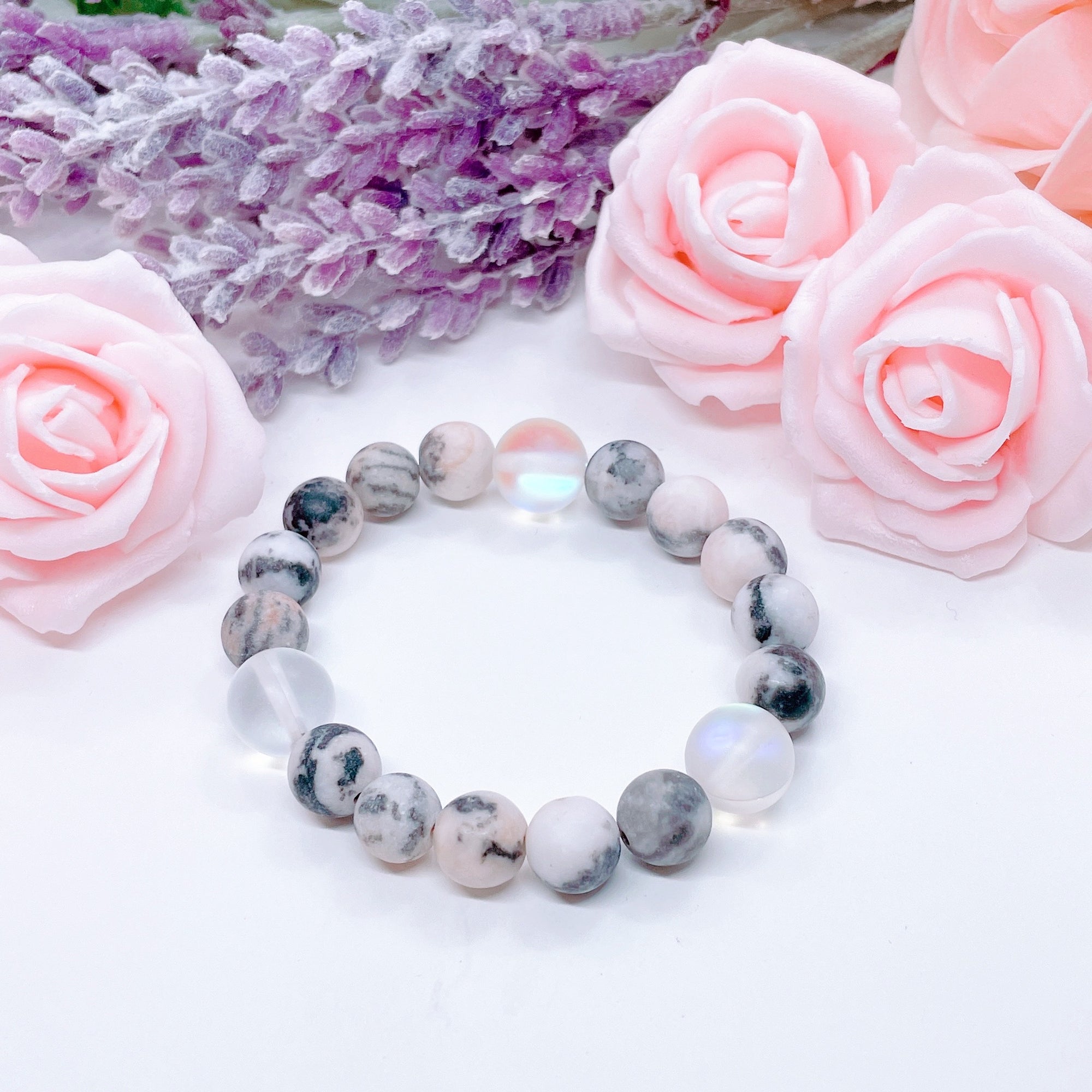 The original 5 Second Rule gemstone stretch bracelet made with pink zebra jasper beads and translucent aura beads sits on a white table. Natural neutral colors.