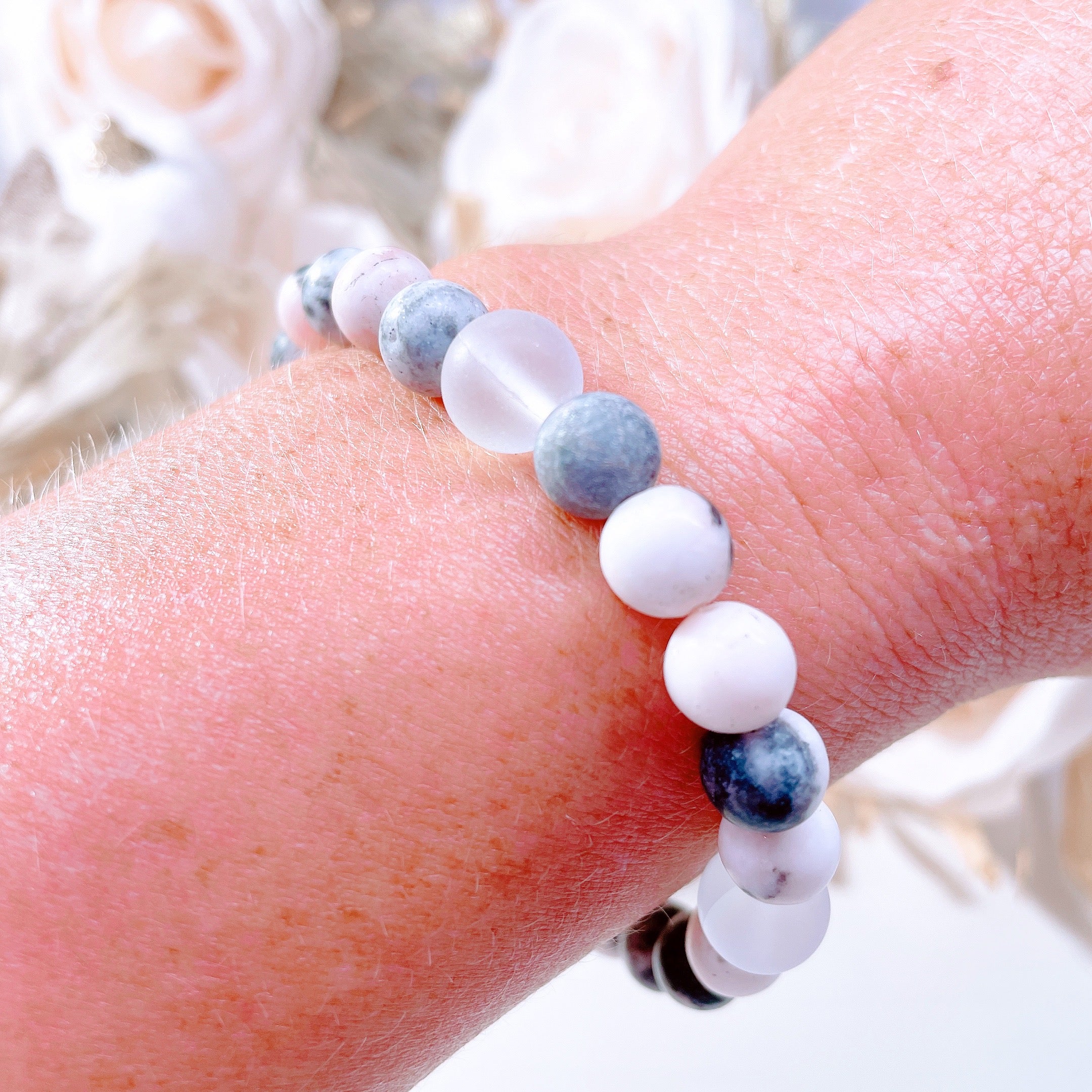 The original 5 Second Rule gemstone stretch bracelet made with pink zebra jasper beads and translucent aura beads is worn on a wrist. Natural neutral colors.