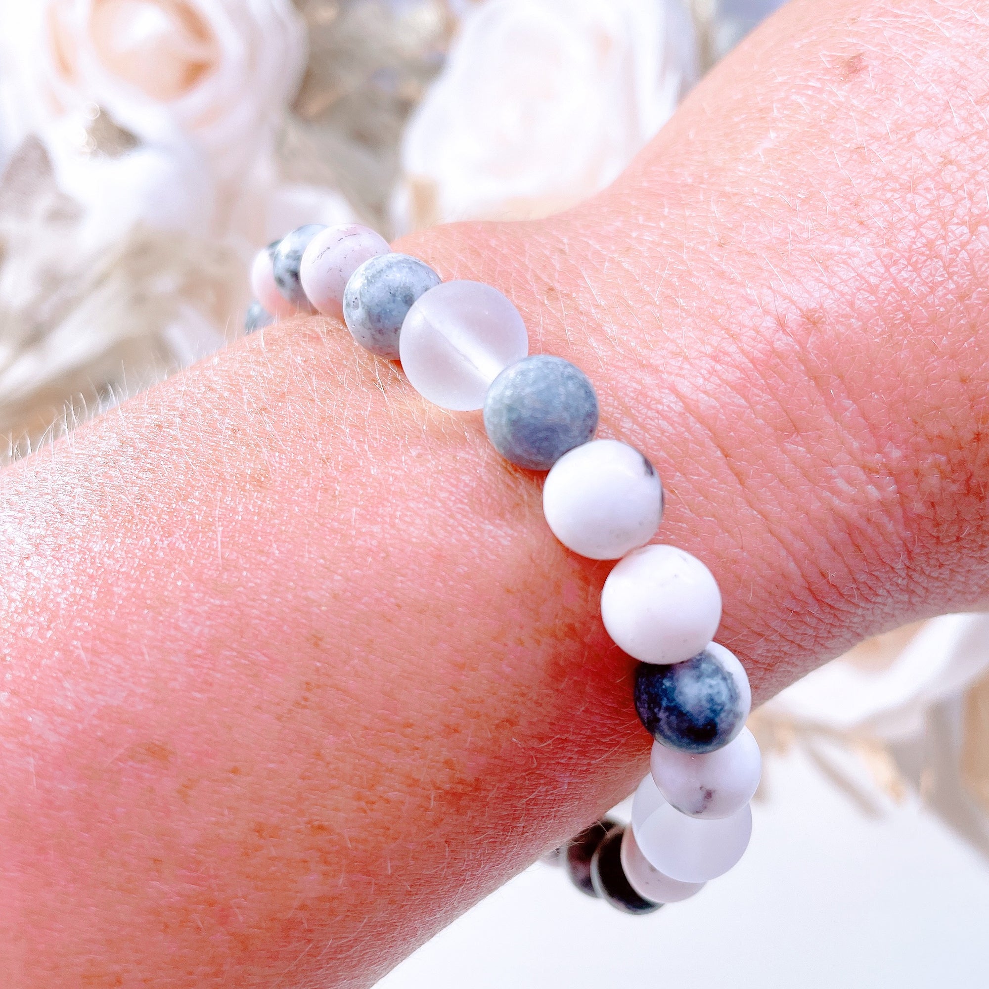 The original 5 Second Rule gemstone stretch bracelet made with pink zebra jasper beads and translucent aura beads is worn on a wrist. Natural neutral colors.