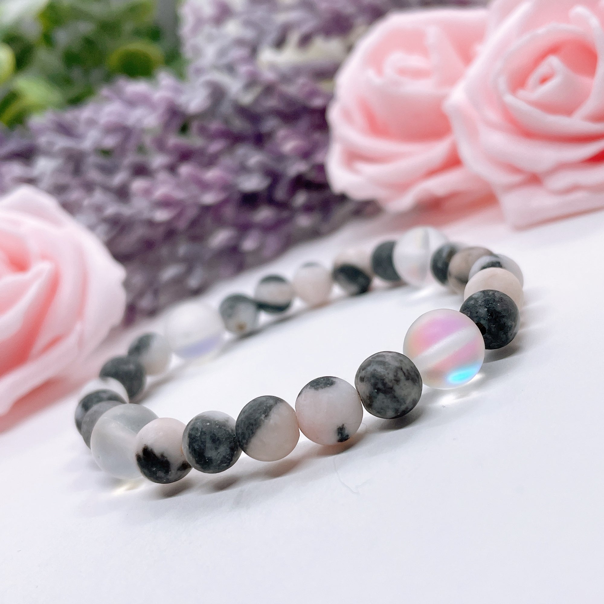 The 5 Second Rule Companion gemstone stretch bracelet made with pink zebra jasper beads and translucent aura beads sits on a white table. Natural neutral colors.
