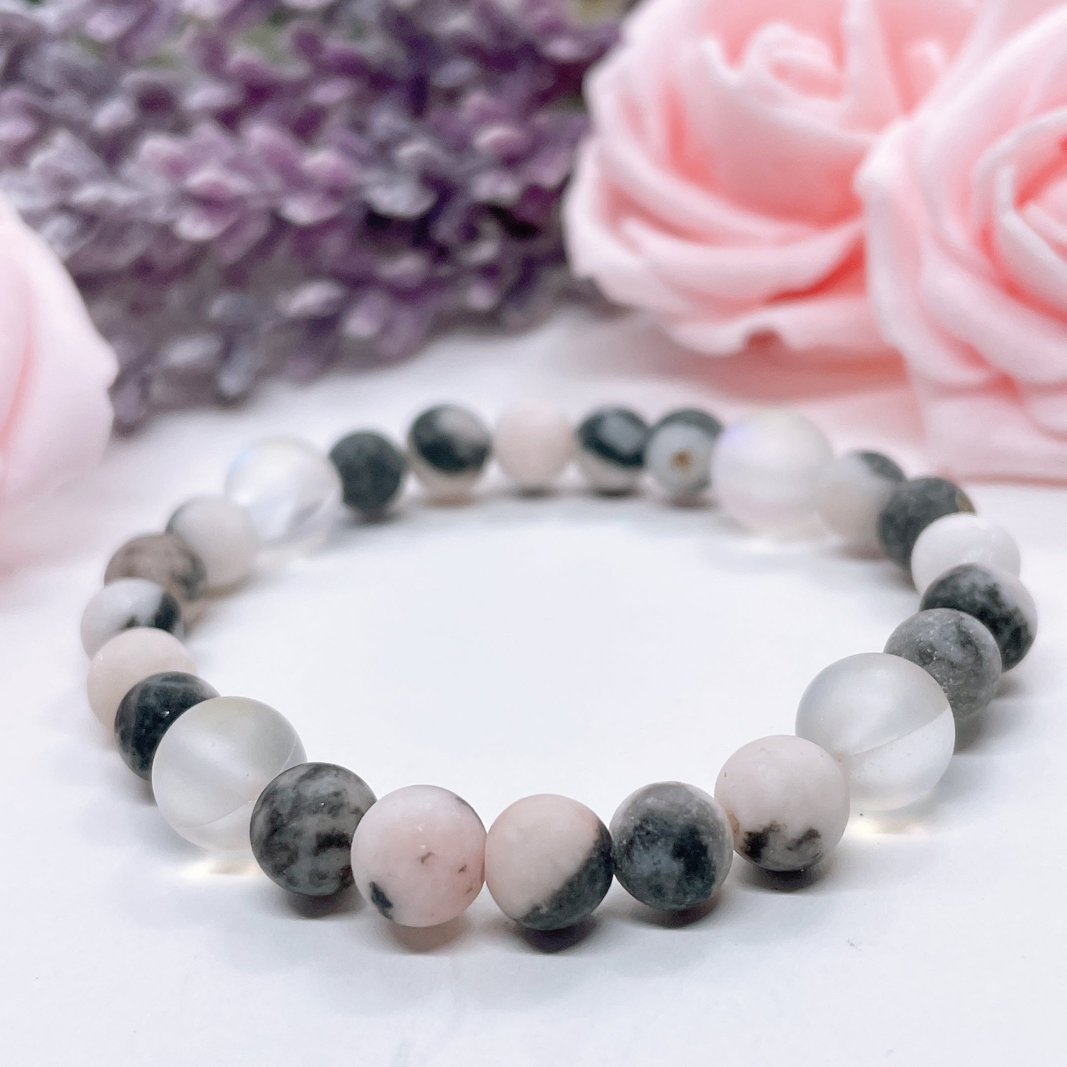 The 5 Second Rule Companion gemstone stretch bracelet made with pink zebra jasper beads and translucent aura beads sits on a white table. Natural neutral colors.