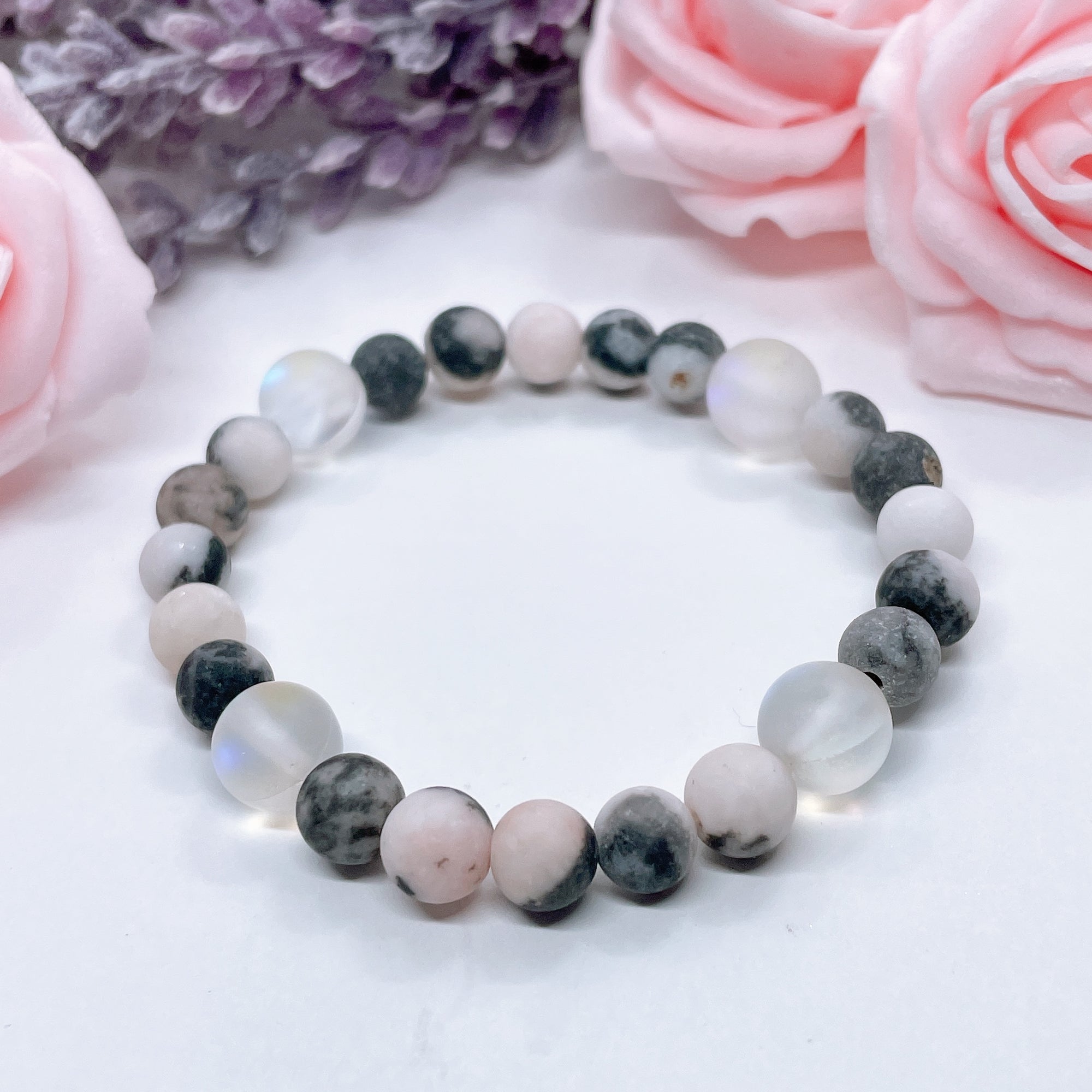 The 5 Second Rule Companion gemstone stretch bracelet made with pink zebra jasper beads and translucent aura beads sits on a white table. Natural neutral colors.