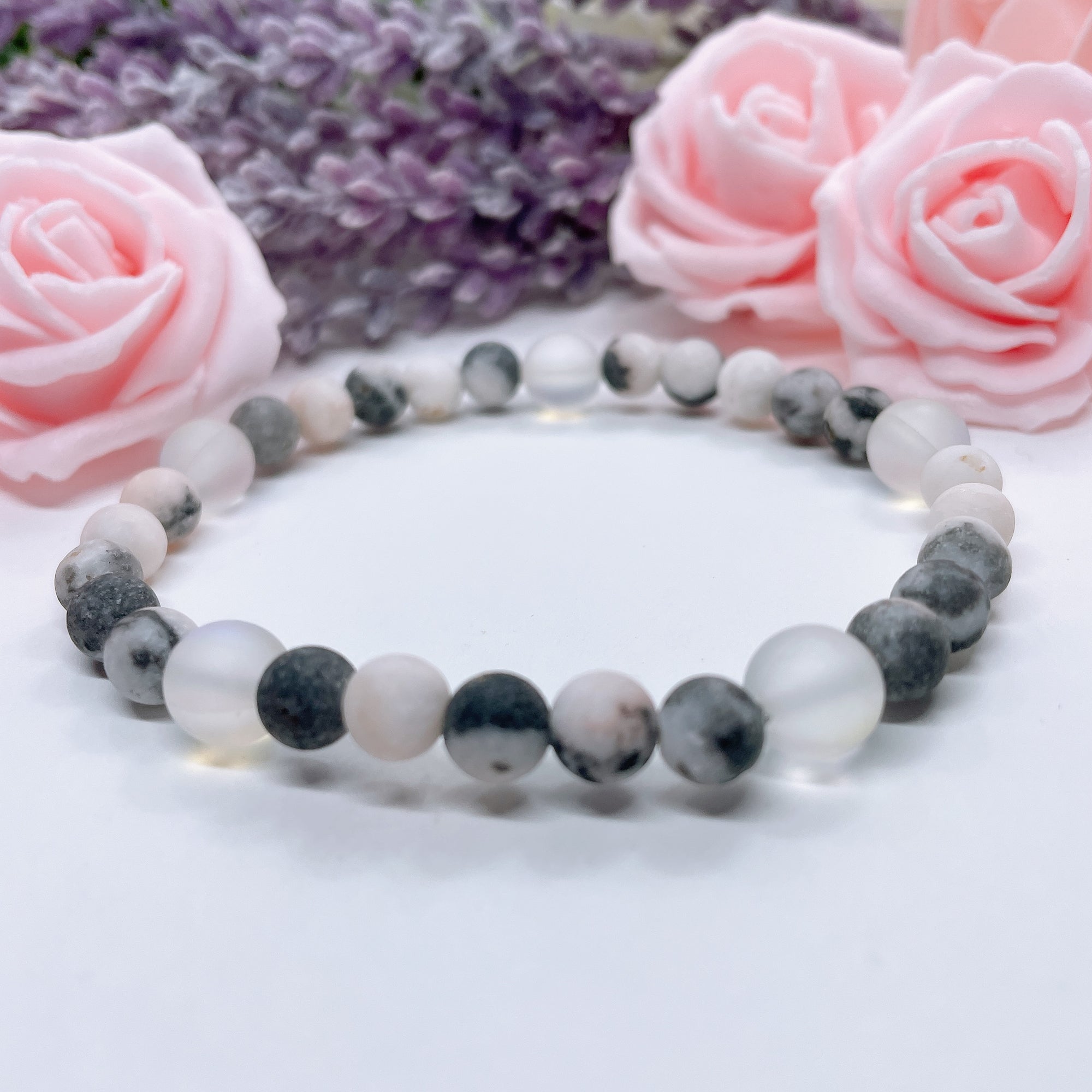 The 5 Second Rule Companion gemstone stretch bracelet made with pink zebra jasper beads and translucent aura beads sits on a white table. Natural neutral colors.