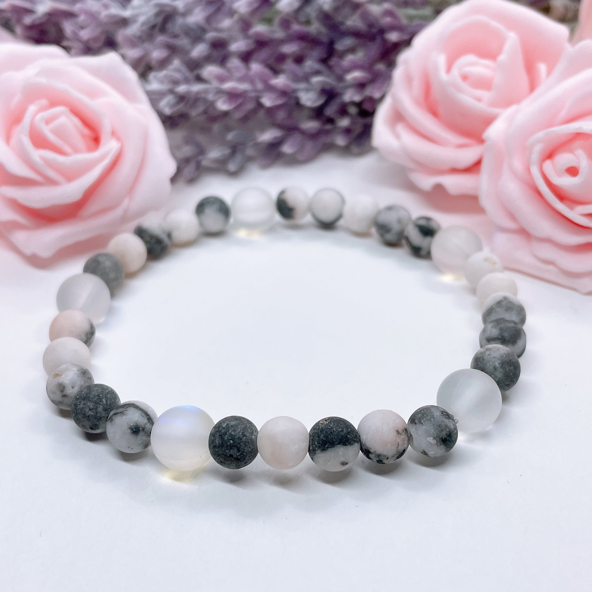 The 5 Second Rule Companion gemstone stretch bracelet made with pink zebra jasper beads and translucent aura beads sits on a white table. Natural neutral colors.