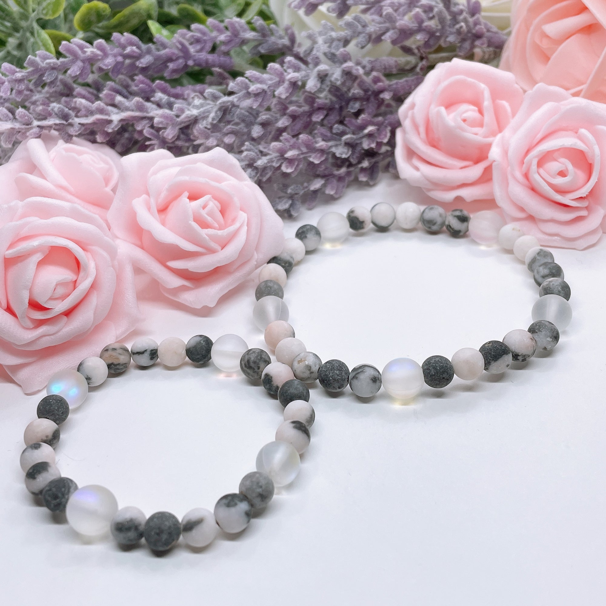 The 5 Second Rule Companion gemstone stretch bracelet made with pink zebra jasper beads and translucent aura beads sits on a white table. Natural neutral colors.