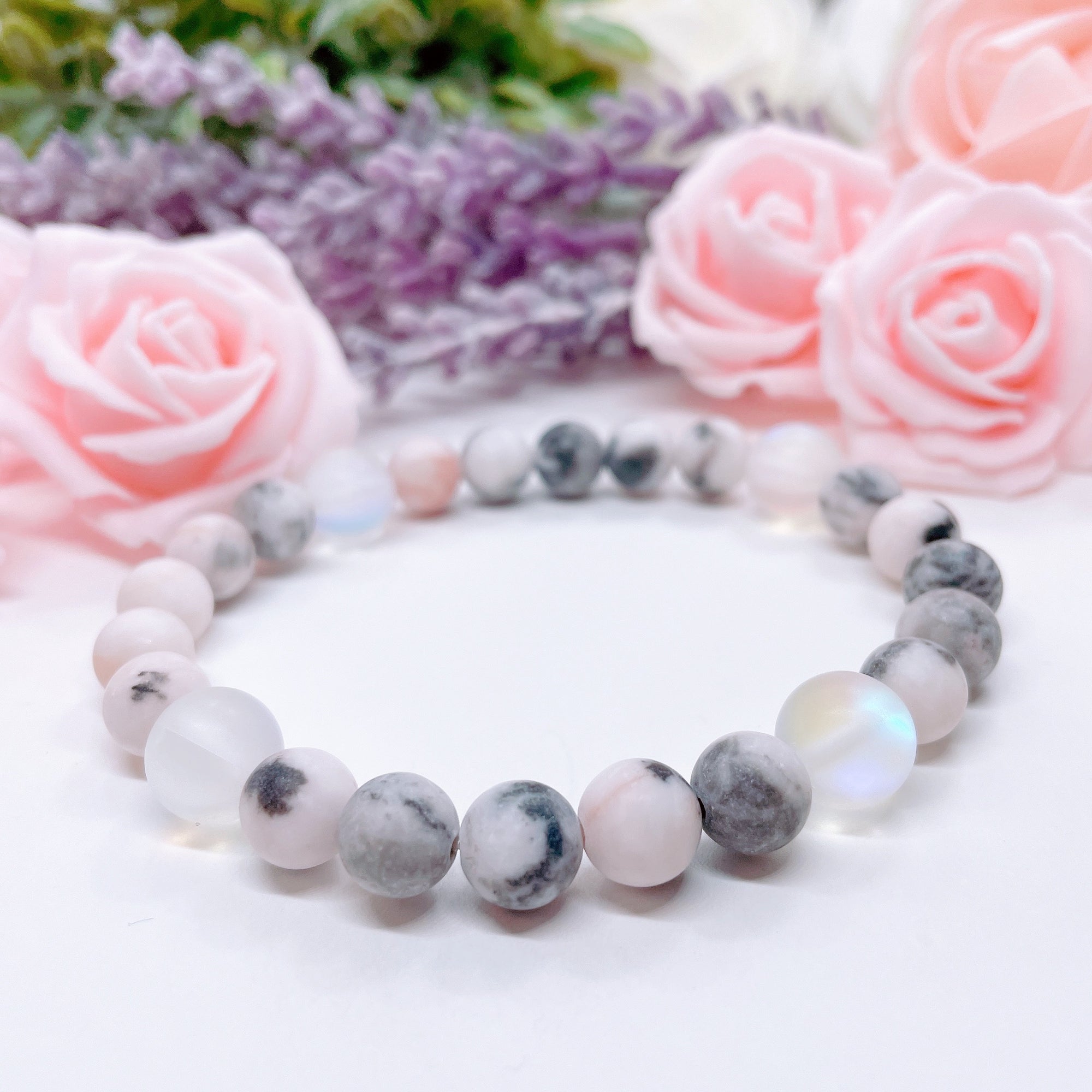 The original 5 Second Rule gemstone stretch bracelet made with pink zebra jasper beads and translucent aura beads sits on a white table. Natural neutral colors.