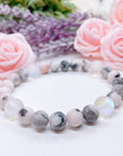 The original 5 Second Rule gemstone stretch bracelet made with pink zebra jasper beads and translucent aura beads sits on a white table. Natural neutral colors.