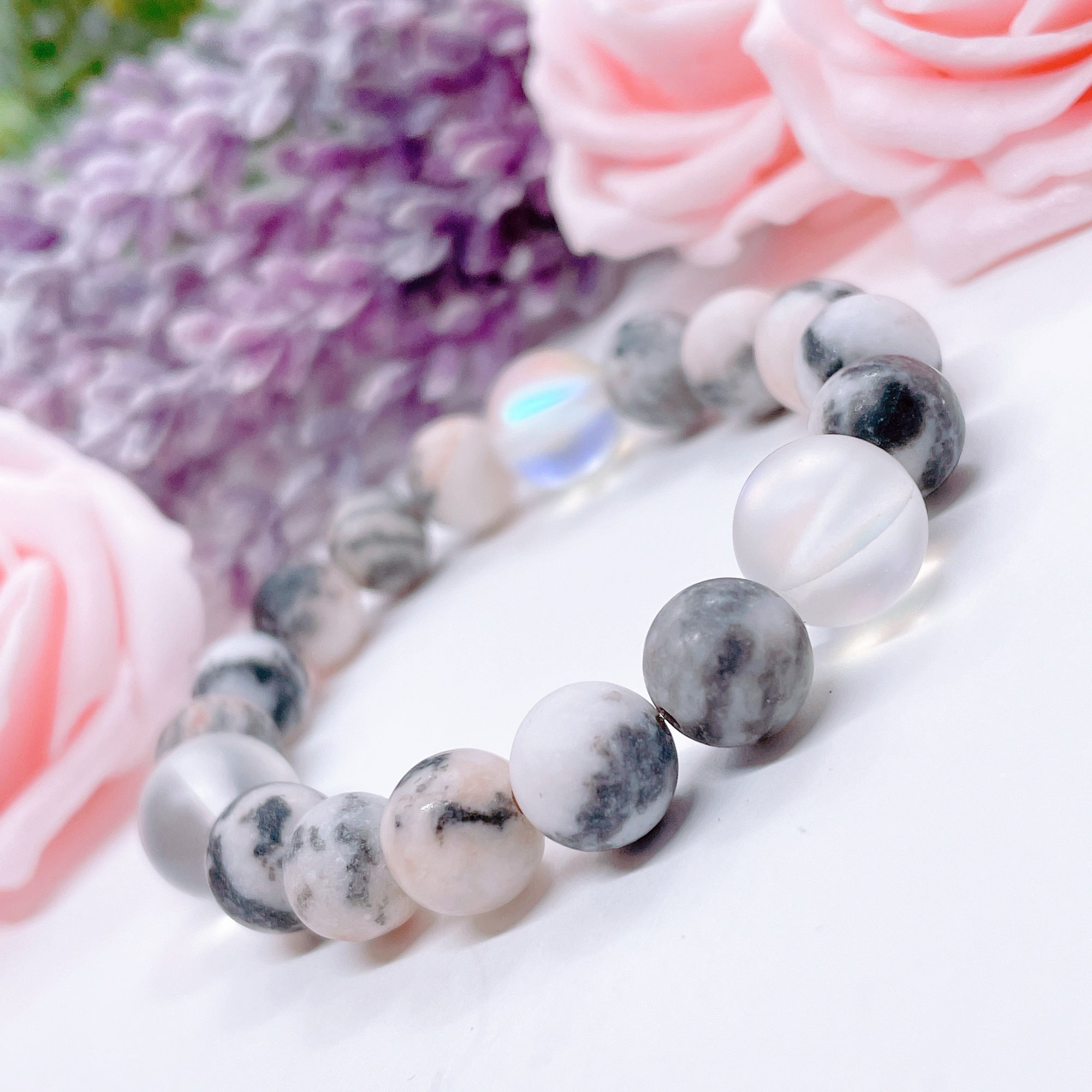 The original 5 Second Rule gemstone stretch bracelet made with pink zebra jasper beads and translucent aura beads sits on a white table. Natural neutral colors.